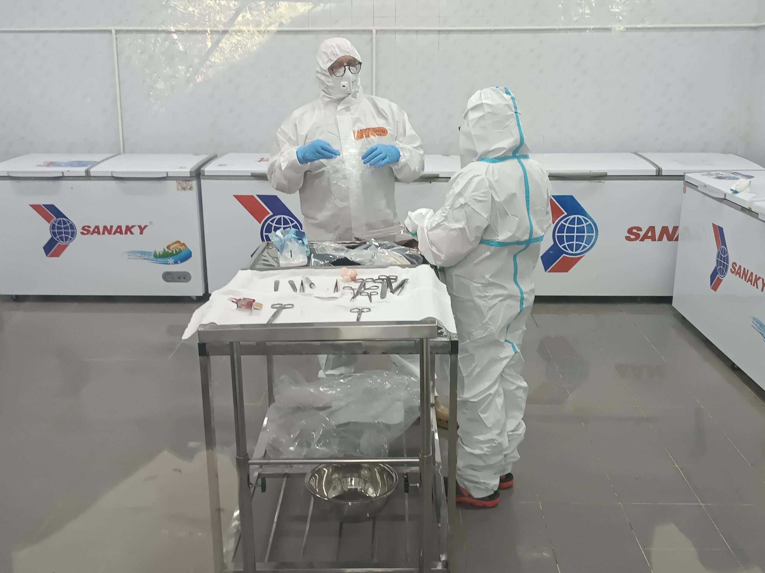 Two researchers in protective coverall are standing in the pathology at an operation table